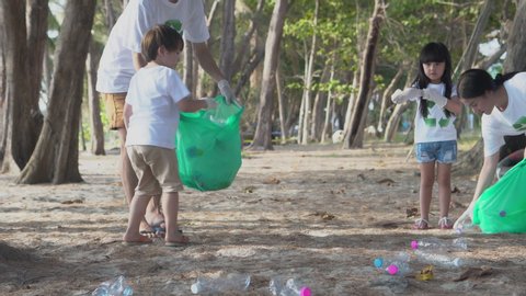 Happy asian family team volunteer keeping garbage and plastic bottle while cleaning on beach for reduce pollution and toxic and recycle to environment for protect and help social in summer together.