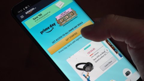 Montreal, Canada - May 28, 2020 : A hand scrolling through deals in Amazon application on Amazon Prime Day.  Amazon Prime Day is the retailer's big members-only summer sale in month of July each year