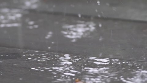 Slow motion speed close up scene on raindrop fall against and bounce on floor, flood from rainstrom in bad rainy day, natural pattern of pouring rain bumping on ground, grainy texture of water