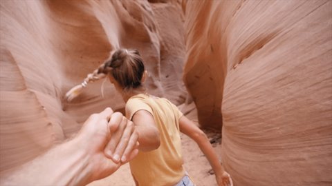 Follow me to concept: young woman holding companion's hand leading the way to stunning narrow canyon. Personal perspective of hiker giving hand to partner traveling together. Slow motion 