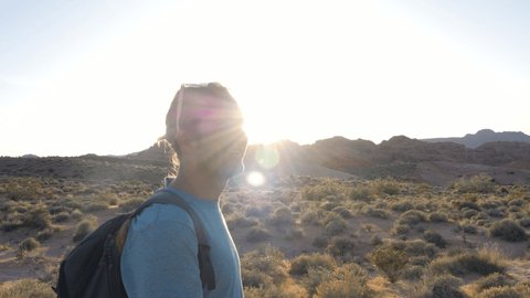 Man hiking in desert settings at sunset. Young adventurous man exploring and walking on trail in Valley of Fire State Park in USA 