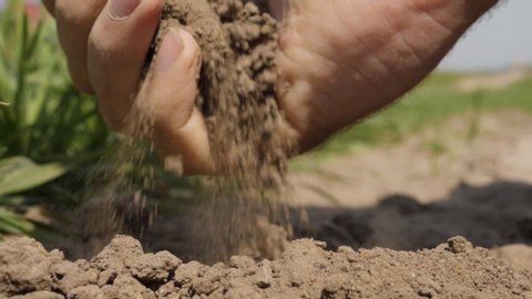 Natural Organic Soil Agriculture. Man Farmer Hands Touching Ground on Field. Close up. Farmer Hands Holding and Pouring Back Organic Soil. Slow Motion. Macro shooting.