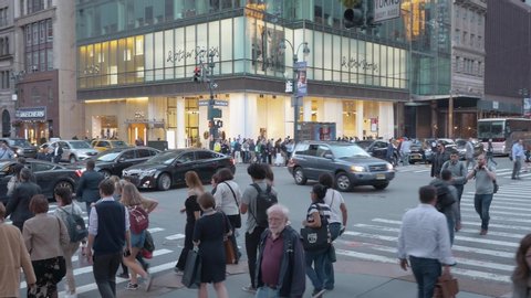 NEW YORK CITY - OCTOBER 2016: Panning left of crowds of people crossing streets in Midtown Manhattan on 42nd street and Fifth Avenue intersection in New York City, USA