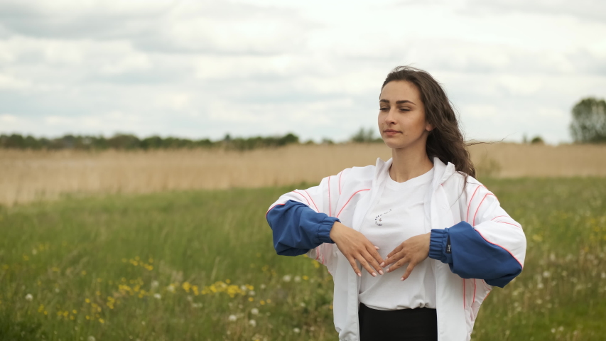 25 year old girl of sporty appearance is doing a warm-up in the park near the lake