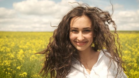 Happy girl on a spring yellow rapeseed spinning in front of the camera