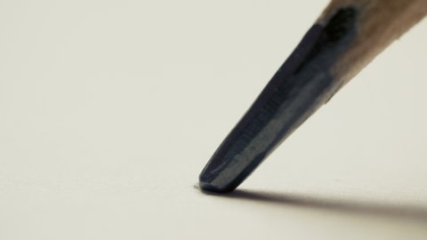 Graphite pencil draws a dot circle line on a white background paper, macro shot