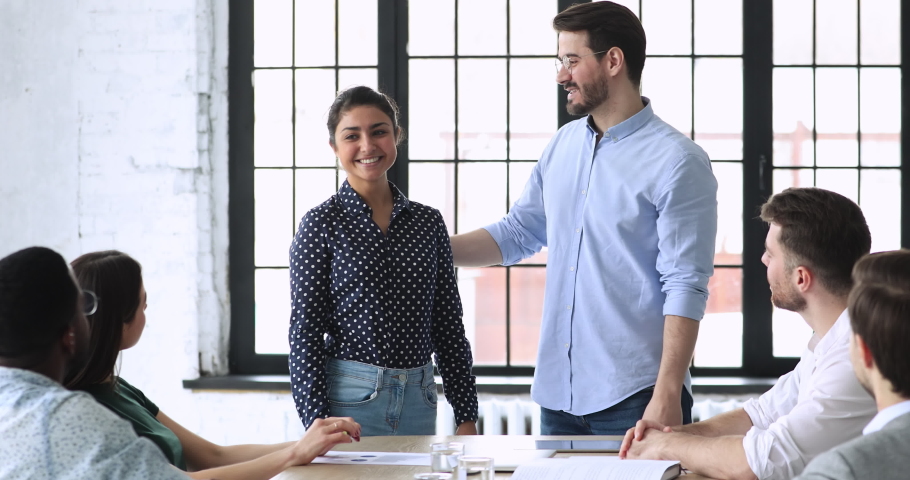 Friendly young business people welcoming new indian employee at workplace. Smiling confident male boss leader introducing happy female hindu newcomer to group of diverse teammates at first workday. Royalty-Free Stock Footage #1053336137