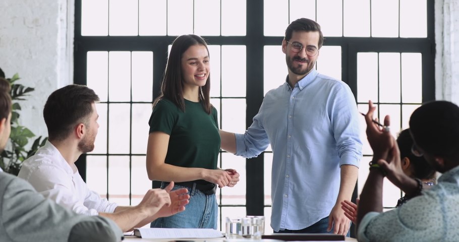Smiling young male team leader boss introducing new project manager to multiracial colleagues in office. Pleasant female newcomer having first working day, getting acquainted with diverse coworkers.