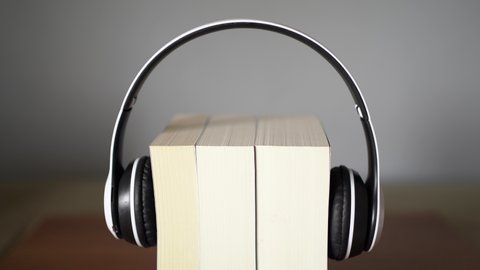 Audio book concept. Putting headphone on the book.