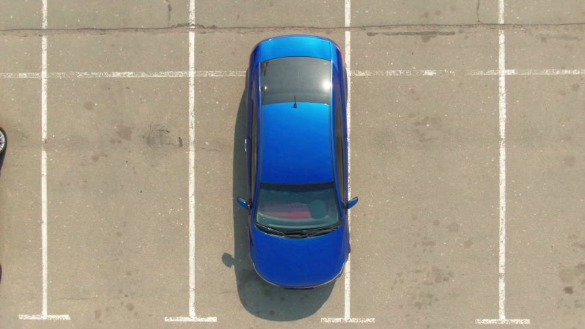 Aerial top view from drone of the shopping mall (supermarket) parking lot with cars and empty parking spots at day. Top view blue car driving out of the parking lot. 4k footage | Shutterstock HD Video #1053339272
