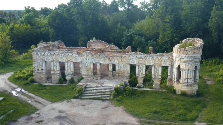 Abandoned ruins of a 19th century manor house among a spring dense forest. Aerial view. 