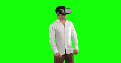 Attractive Caucasian man with short dark hair, wearing a white shirt and using vr goggles, looking at virtual interactive screen on green screen background