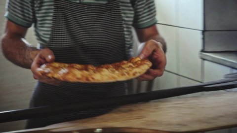 Turkish Muslim baker male takes out traditional Ramadan bread of Turkish cuisine from oven and puts on marble ground at a bakery