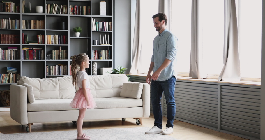 Young smiling father inviting to dance little preschool princess daughter. Happy handsome bearded dad dancing waltz, lifting cute small child girl wearing crown, rehearsing kindergarten performance. Royalty-Free Stock Footage #1053352163