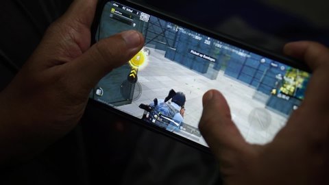 MALAYSIA, Kuala Lumpur, May 28, 2020 : Hands of teens holding Android smartphones playing PUBG Mobile battle royale game.