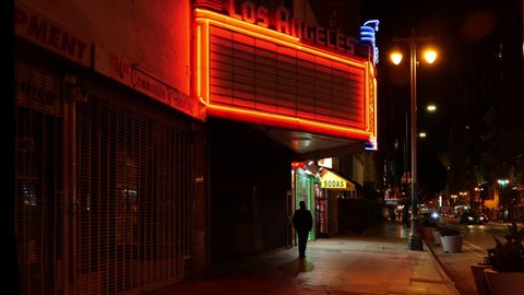 Los Angeles, CA/USA - May 20, 2020: A lone man walks in the Broadway Theatre District at night during coronavirus quarantine