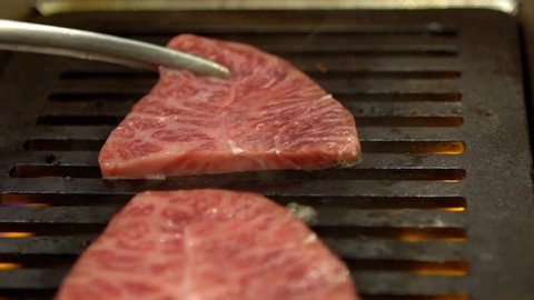 Thinly sliced Japanese wagyu beef on grille for barbecue. Grill one of the best beef in Japan. Style Yakiniku meaning grilled meat cuisine. BBQ food.-Dan