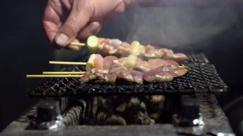 Slow motion of chef cooking inside izakaya Japanese bar in Tokyo. Traditional meat skewers being grilled in a barbecue. Japan at street food vendor market.-Dan