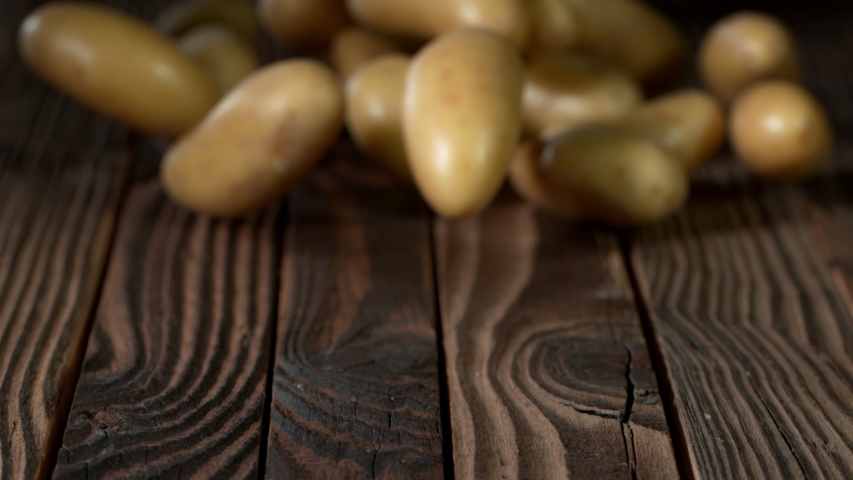 Super Slow Motion Shot of Potatoes Rolling on Old Wooden Table at 1000fps. Royalty-Free Stock Footage #1053362021