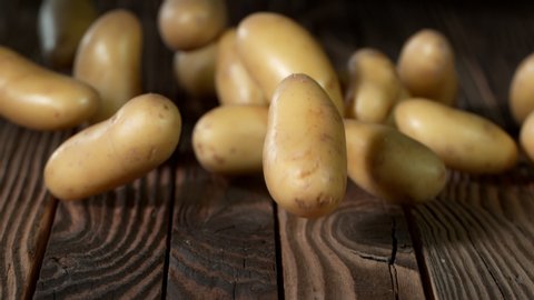 Super Slow Motion Shot of Potatoes Rolling on Old Wooden Table at 1000fps.
