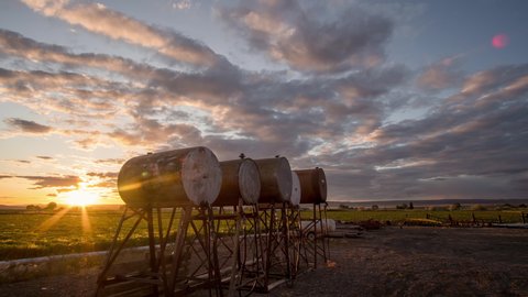 Time lapse of colorful sunset on farm in Southern Idaho with fuel tanks in view as the sky changes color.