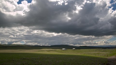 Time lapse of farm with rolling hills as clouds move through the sky over field growing peas in Idaho.