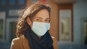 Portrait of a Beautiful Dark Haired Young Woman Wearing Protective Medical Face Mask and Standing on the Street. Safe and Happy Woman Practicing Social Distancing, Quarantine. Blurred City Background - Powered by Shutterstock - Get 15% off with code: PIKWIZARD15