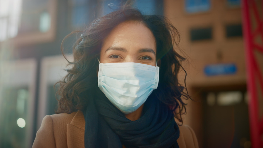 Portrait of a Beautiful Dark Haired Young Woman Wearing Protective Medical Face Mask and Standing on the Street. Safe and Happy Woman Practicing Social Distancing, Quarantine. Blurred City Background Royalty-Free Stock Footage #1053374321