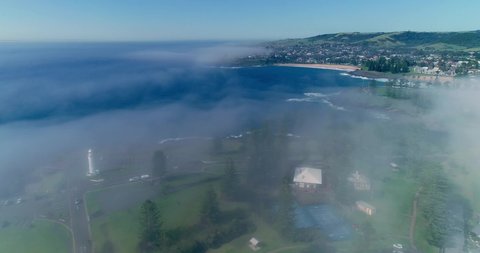 Decending through light morning ocean mist above Kiama Rock Pool looking South over the Kiam Lighthouse across Storm Bay to Kendalls Beach, and Kaleula Head on a glorious sunny morning with blu