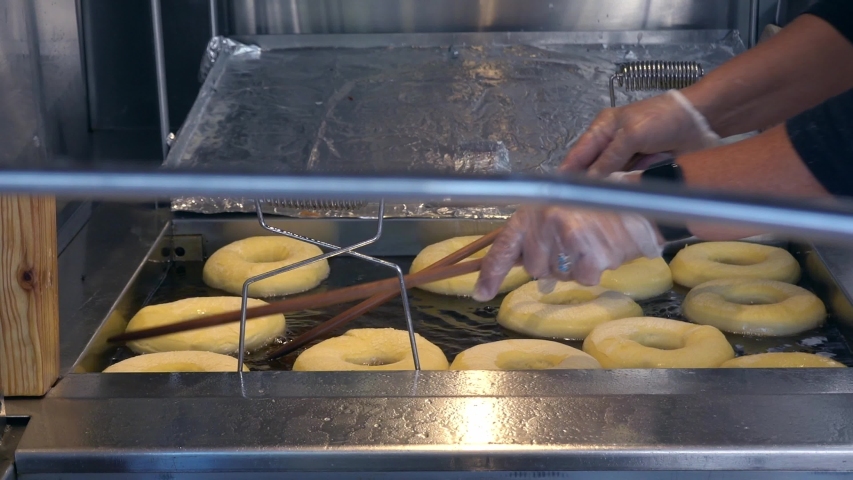 Doughnuts in a fryer being flipped. Shot at a vendor booth at the North Carolina State Fair. Royalty-Free Stock Footage #1053387389