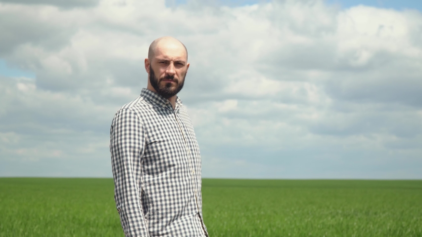 Portrait of farmer man with beard looking to camera in wheat field. Farmer examines the field of cereals