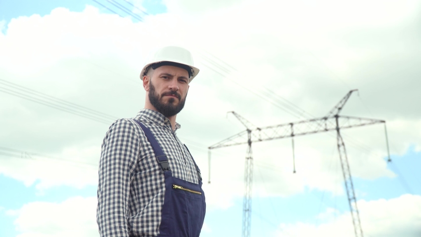 Portrait of engineer near transmission lines. Energy efficiency conception. Transmission towers