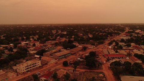 Aerial rise up over Bakoteh in Serrekunda The Gambia during dusk and orange lit skies from cloud cover