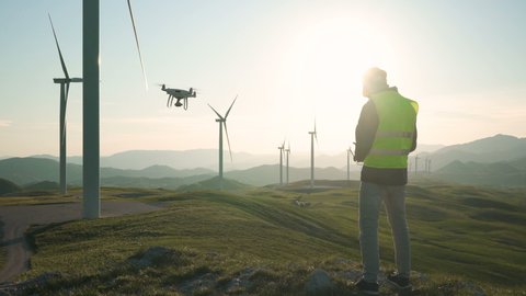 Technician Engineer in Wind Turbine Power Generator Station launches a drone for visual control of generators