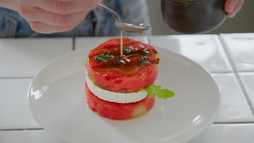 Woman practice high cuisine recipe from internet food blog, learn new skill from video or workshop. Decorate the dish with fresh herbs and nuts, vegeterian plate or dish looks delicious and tasty