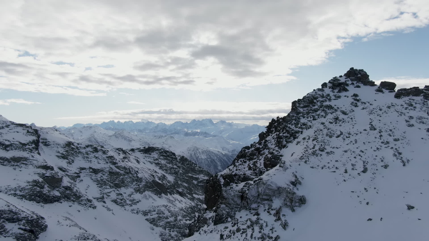 Snowy mountains against cloudy sky around drone view of amazing mountain ridge of Alps covered with snow on cloudy day in Courchevel, France Royalty-Free Stock Footage #1053403517