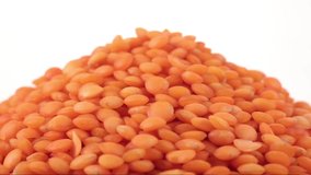 Red lentil grains of spin around themselves on white background