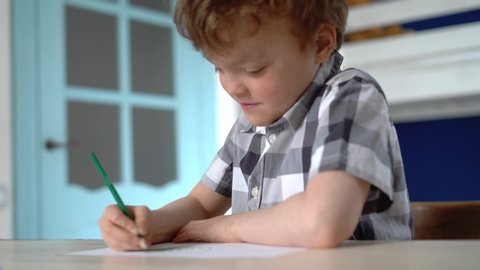A child paints a drawing with a green pencil.