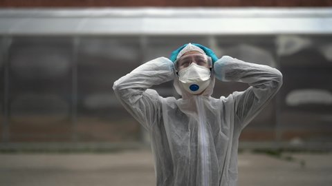 Exhausted crying doctor/nurse in coronavirus protective gear N95 mask.Covid-19 pandemic outbreak.Fatalities grief.Frontline worker mental stress,burnout.Mental breakdown.Overworked healthcare provider