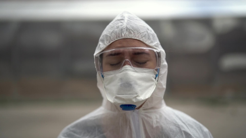Exhausted crying doctor/nurse in coronavirus protective gear N95 mask.Covid-19 pandemic outbreak.Fatalities grief.Frontline worker mental stress,burnout.Face mask scars.Overworked healthcare provider	 | Shutterstock HD Video #1053409043