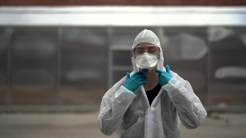 COVID-19 coronavirus doctor in hazmat suit.Infectious disease pandemic medical worker.Female physician in uniform on frontline,fighting viral outbreak.Protective suit with N95 mask.	 | Shutterstock HD Video #1053409046