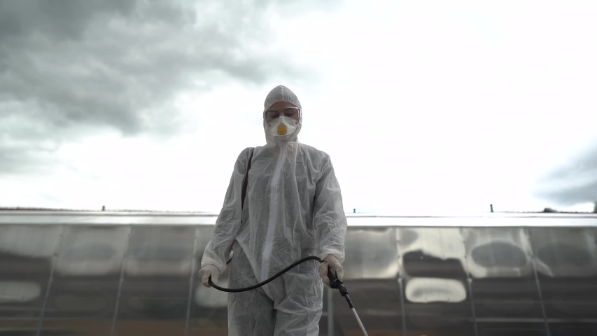 Professional disinfector in hazmat protection suit and N95 mask with chemical decontamination sprayer tank.Disinfecting streets and public areas to stop COVID-19 .Coronavirus disinfection concept | Shutterstock HD Video #1053409070