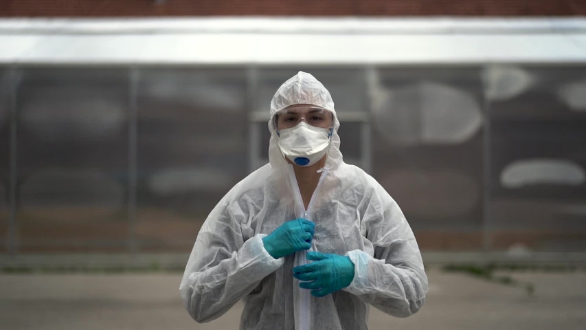 COVID-19 coronavirus doctor in hazmat suit.Infectious disease pandemic medical worker.Female physician in uniform on frontline,fighting viral outbreak.Protective suit with N95 mask.	 | Shutterstock HD Video #1053409088