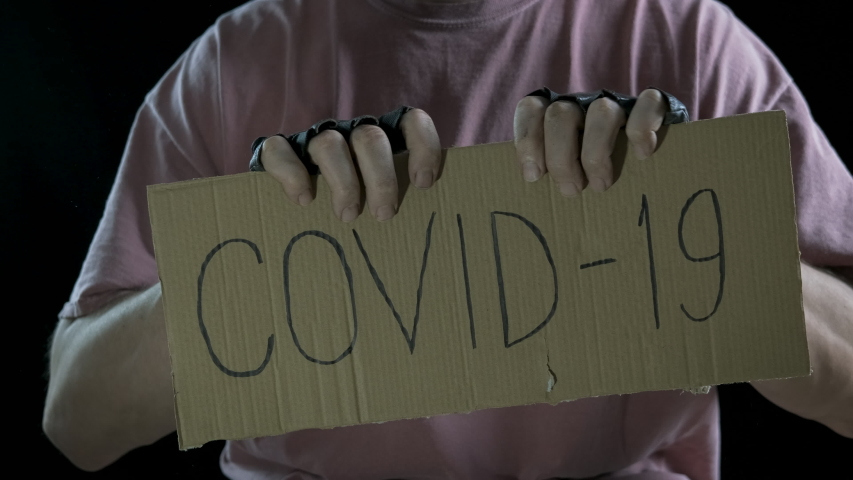 Virus poverty. A hopeless man rips the cardboard in half with the words covid-19. A concept of the end of coronavirus epidemic.
