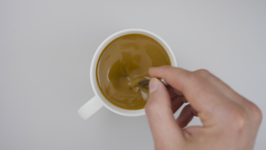 Male hand cup of Hot coffee Closeup Top view. Business and Drink Concepts. Top view of person hand stirring coffee with spoon on gray wooden table. Close up. Slow Motion. | Shutterstock HD Video #1053420044