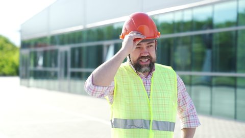 A man wearing a construction helmet and knocks on it. safety during construction work. demonstration of the reliability of the headgear.