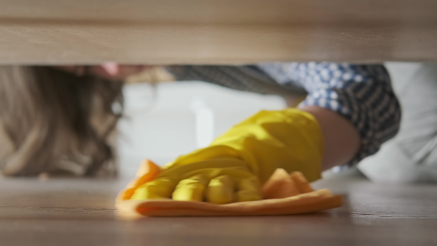 Cleaning and disinfection of surfaces. Woman with yellow rubber gloves and orange rag cleaning floor under bed. Beautiful woman cleaning house. Close-up in 4K, UHD | Shutterstock HD Video #1053427427