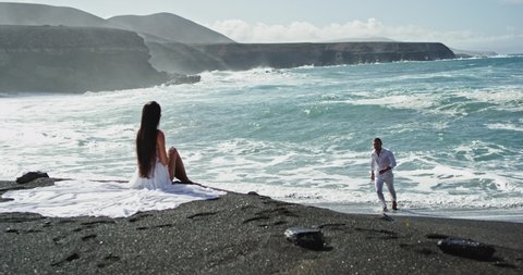 Man and his woman on the beach have a romantic time together with amazing landscape view beautiful black beach and seaside view. Slow motions