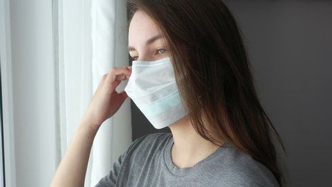 Woman Looking out The Window and Take Off Face Mask from Face. Quarantine End.