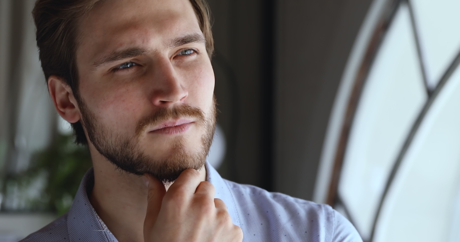 Worried thoughtful young businessman looking away thinking of future business challenges due financial crisis. Doubtful serious entrepreneur lost in thoughts considering risks, opportunities. Close up Royalty-Free Stock Footage #1053432986